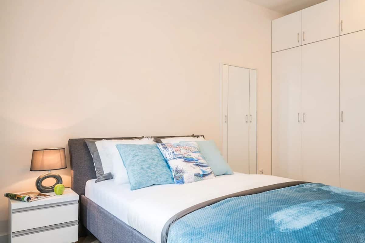 A bedroom with a bed, nightstand, lamp, and wardrobe.