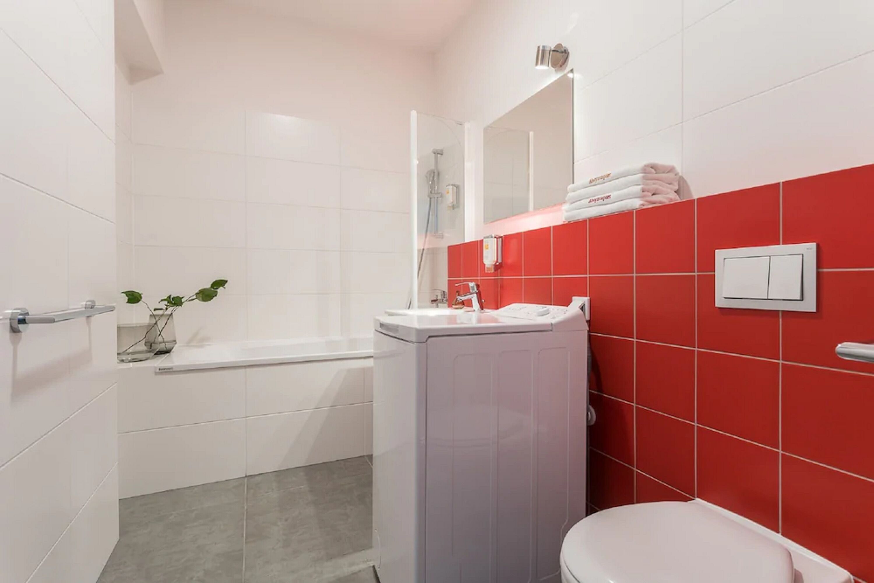 Un baño con una bañera blanca, un inodoro y un lavabo con un espejo encima.