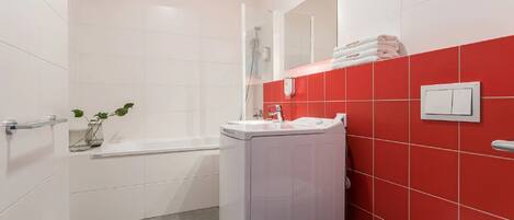 Un baño con una bañera blanca, un inodoro y un lavabo con un espejo encima.