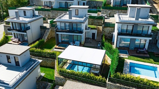 A modern residential complex with multiple two-story houses, each featuring large windows, balconies, and a swimming pool. - Nevras Resort (Sapanca)