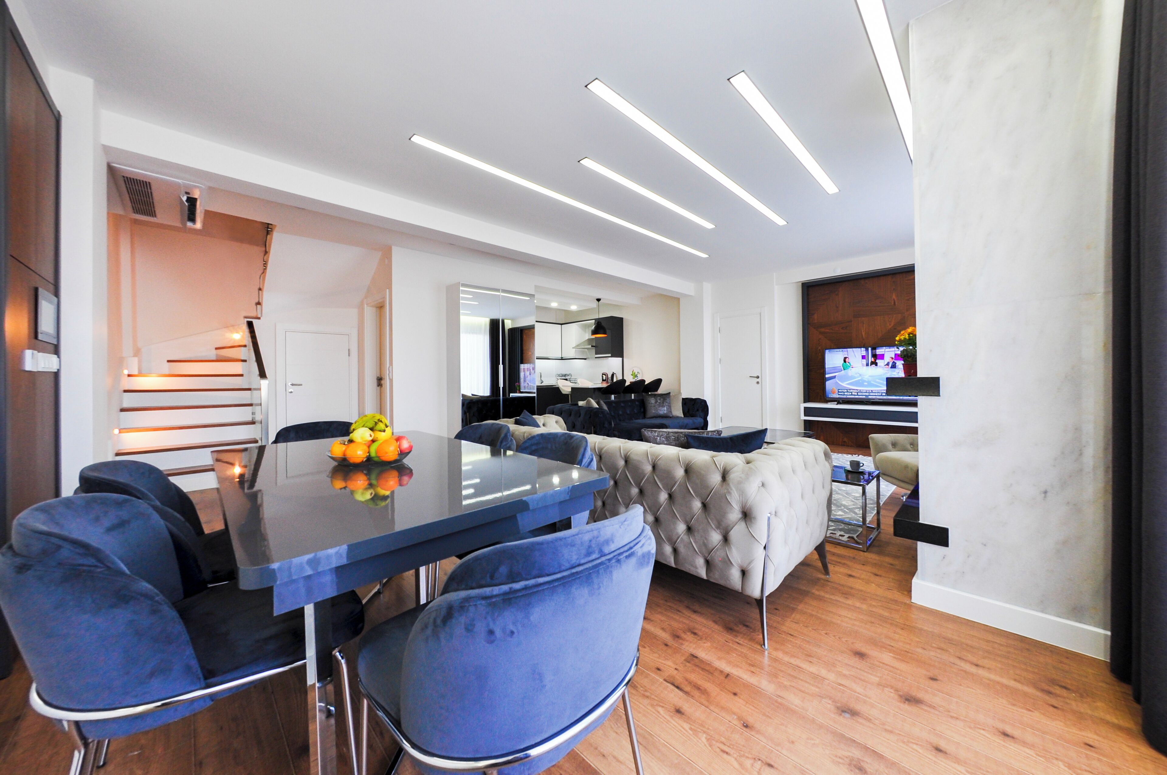 A modern living room with a dining area, a sofa, and a TV.
