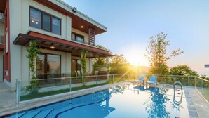A modern house with a swimming pool, outdoor seating, and a view of the sunset. - Nevras Resort (Sapanca)