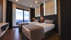 A modern hotel room with two beds, a large window offering a city view, and a built-in TV shelf. - Nevras Resort (Sapanca)