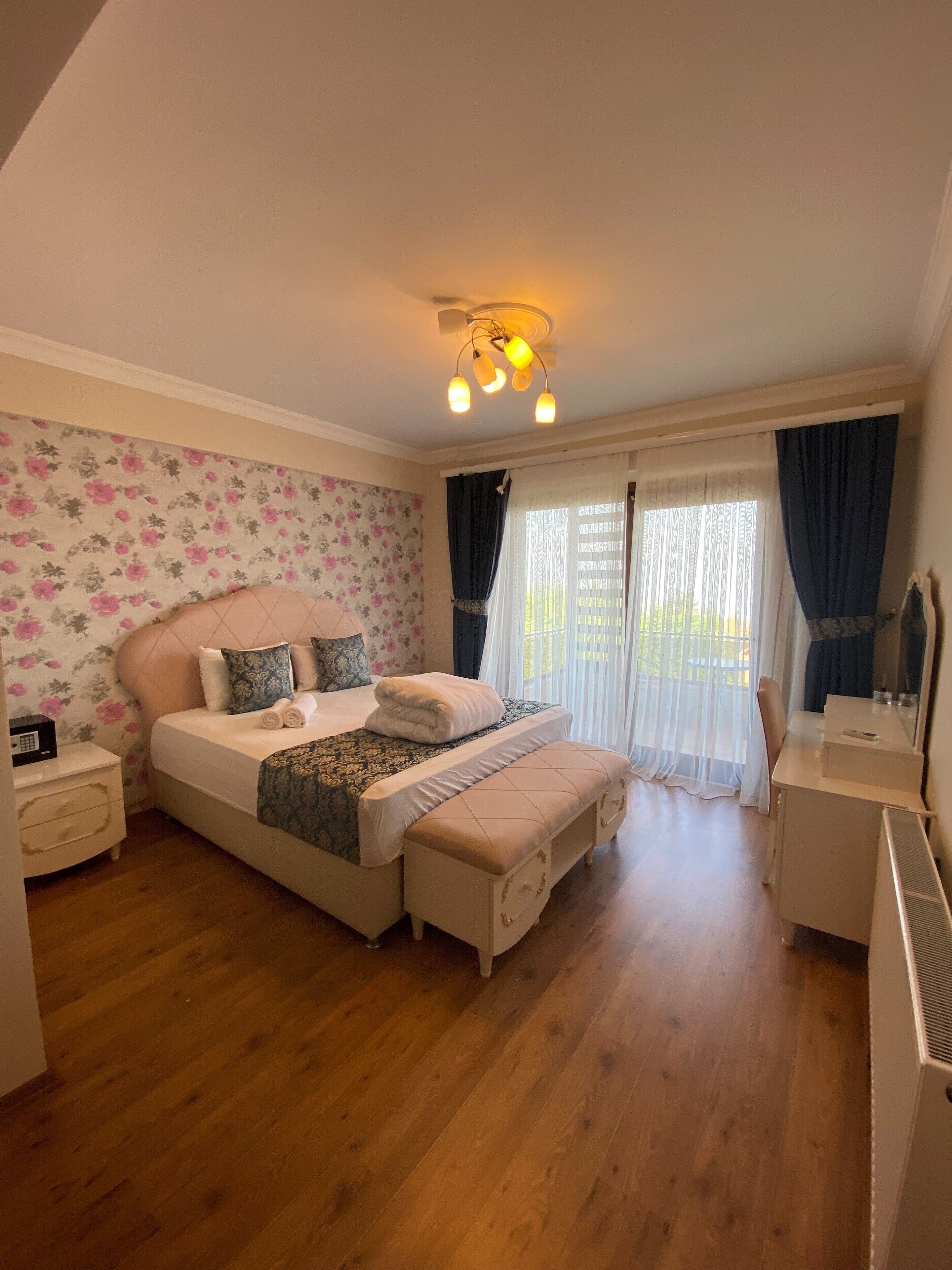 A bedroom with a bed, bedside tables, a bench, a desk, and a radiator.