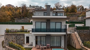 A modern two-story house with a stone facade, a swimming pool, and a staircase leading to the upper level. - Nevras Resort (Sapanca)