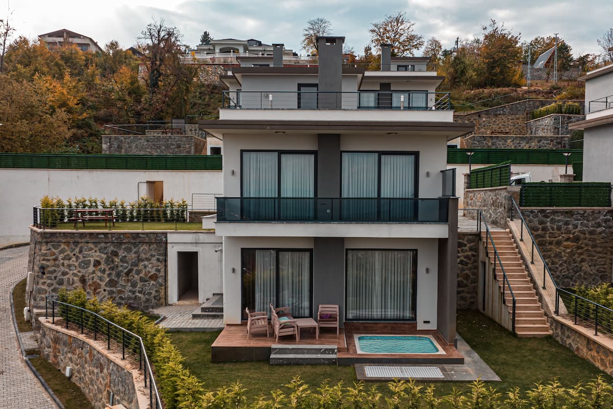 Ein modernes, zweistöckiges Haus mit Naturstein-Fassade, einem Swimmingpool und einer Treppe, die zum Obergeschoss führt.