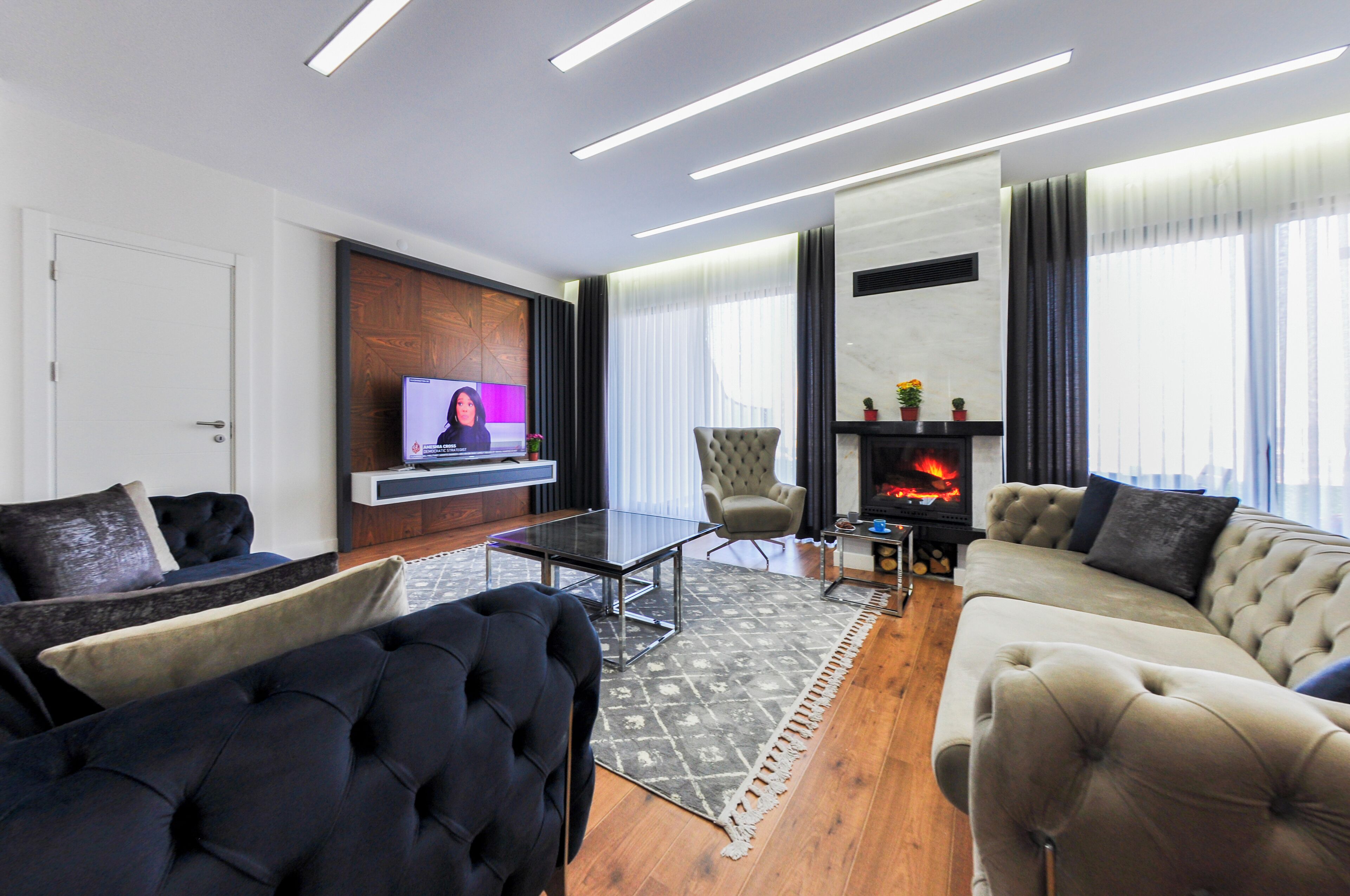 A modern living room with a television, a fireplace, and a sofa.