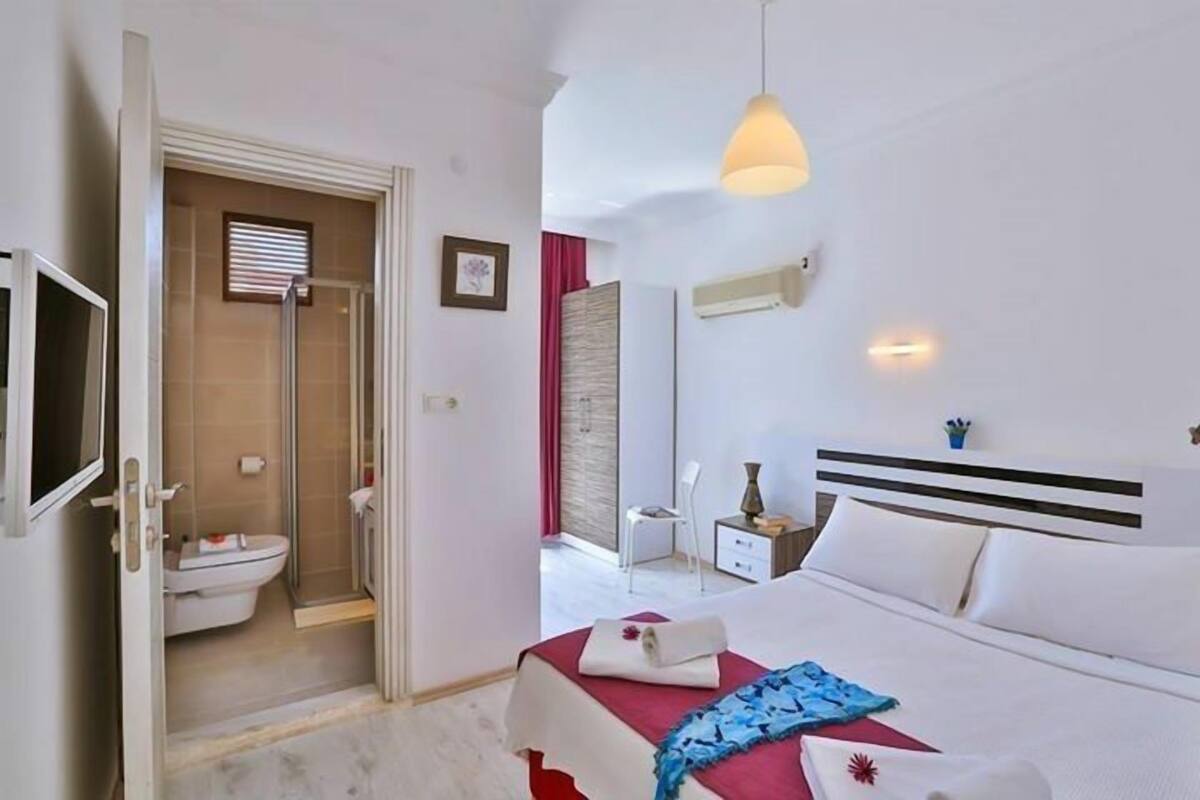Habitación de hotel con cama, mesita de noche y zona de ducha.