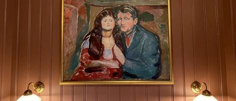 Une chambre à coucher avec un lit, deux lampes fixées au mur et un tableau au-dessus du lit.
