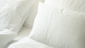 Una cama con ropa de cama y almohadas blancas.