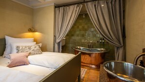 A bedroom with a bed, a large bathtub, and a sink. - Ramme Fjordhotell - Unike Hoteller (Vestby)