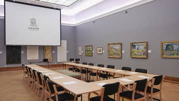 Una sala de conferencias con una larga mesa, sillas y una pantalla que muestra el logotipo de Ramme.