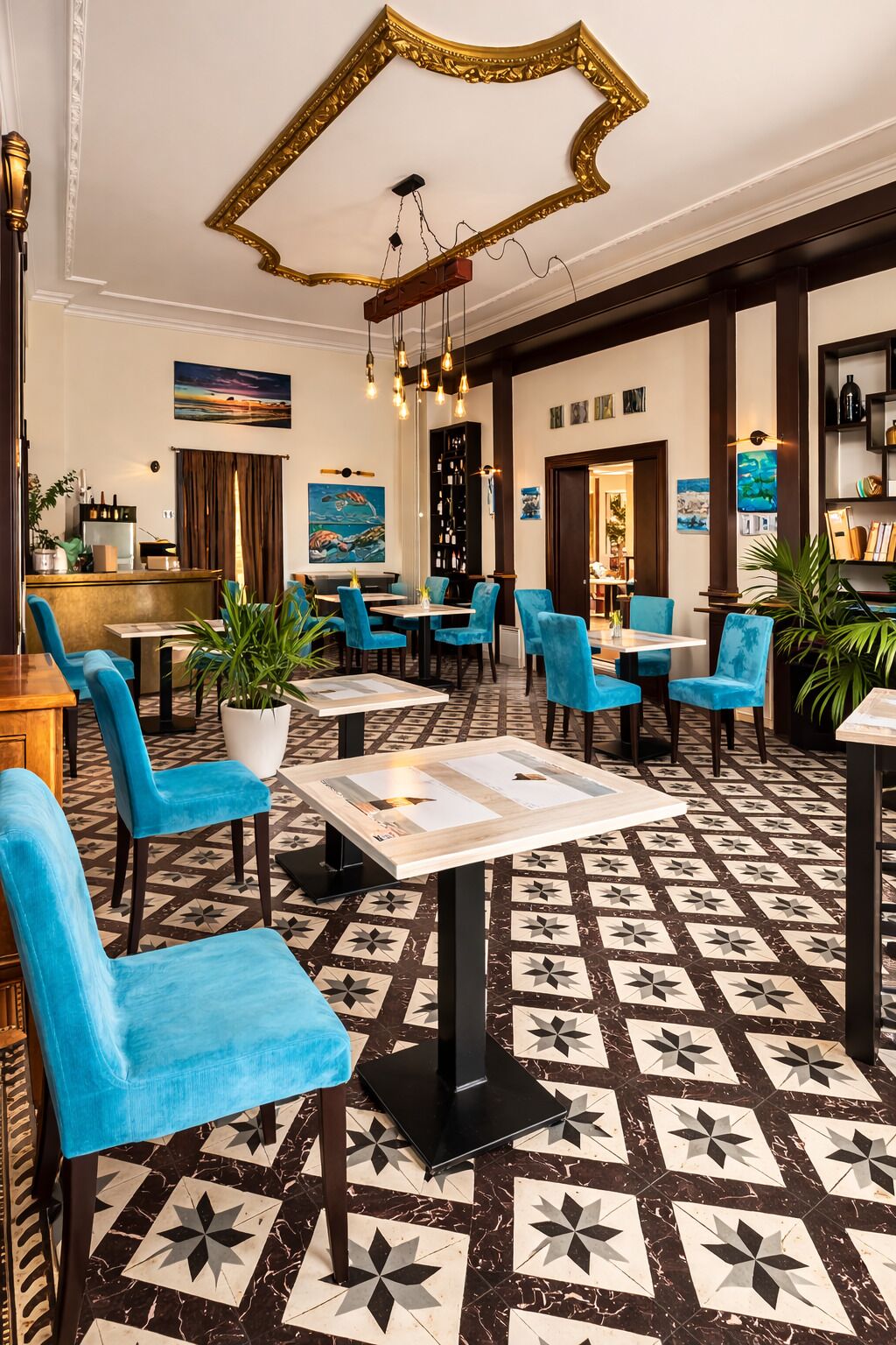A hotel lobby with a patterned floor, blue chairs, a bar area, and artwork on the walls.