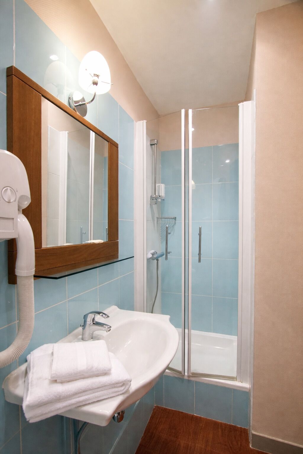 A bathroom with a glass-enclosed shower, a sink with a mirror, and a towel rack.