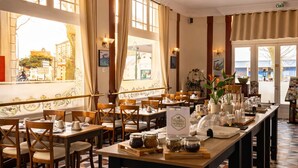 A restaurant with a checkered floor, wooden tables, and chairs. - Logis Hotel Le Majestic (Chatelaillon-Plage)