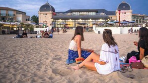 A beach with people sitting and walking, a building with domed roofs, and outdoor seating areas. - Logis Hotel Le Majestic (Chatelaillon-Plage)