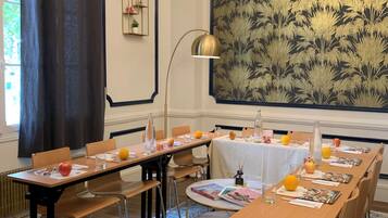 Un comedor con mesas dispuestas para una comida, un amplio muro decorativo y una ventana con cortinas.