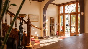 A grand staircase with a statue, a framed picture, and a view of the street outside. - Logis Hotel Le Majestic (Chatelaillon-Plage)