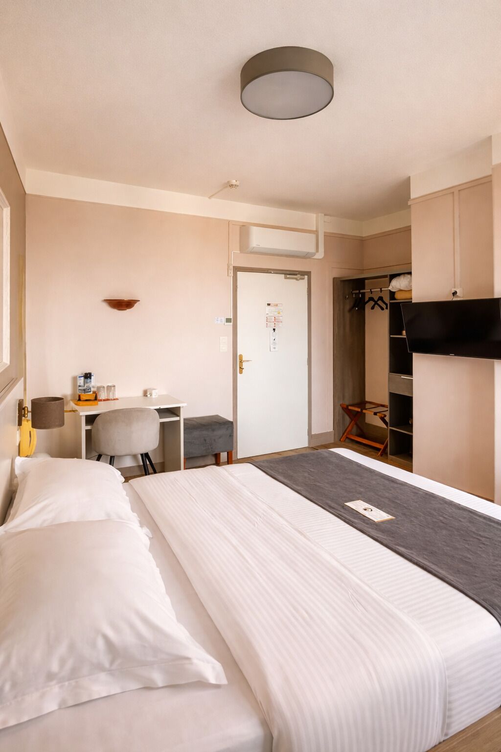 Una camera d'albergo con un letto, una scrivania, una sedia e un armadio.