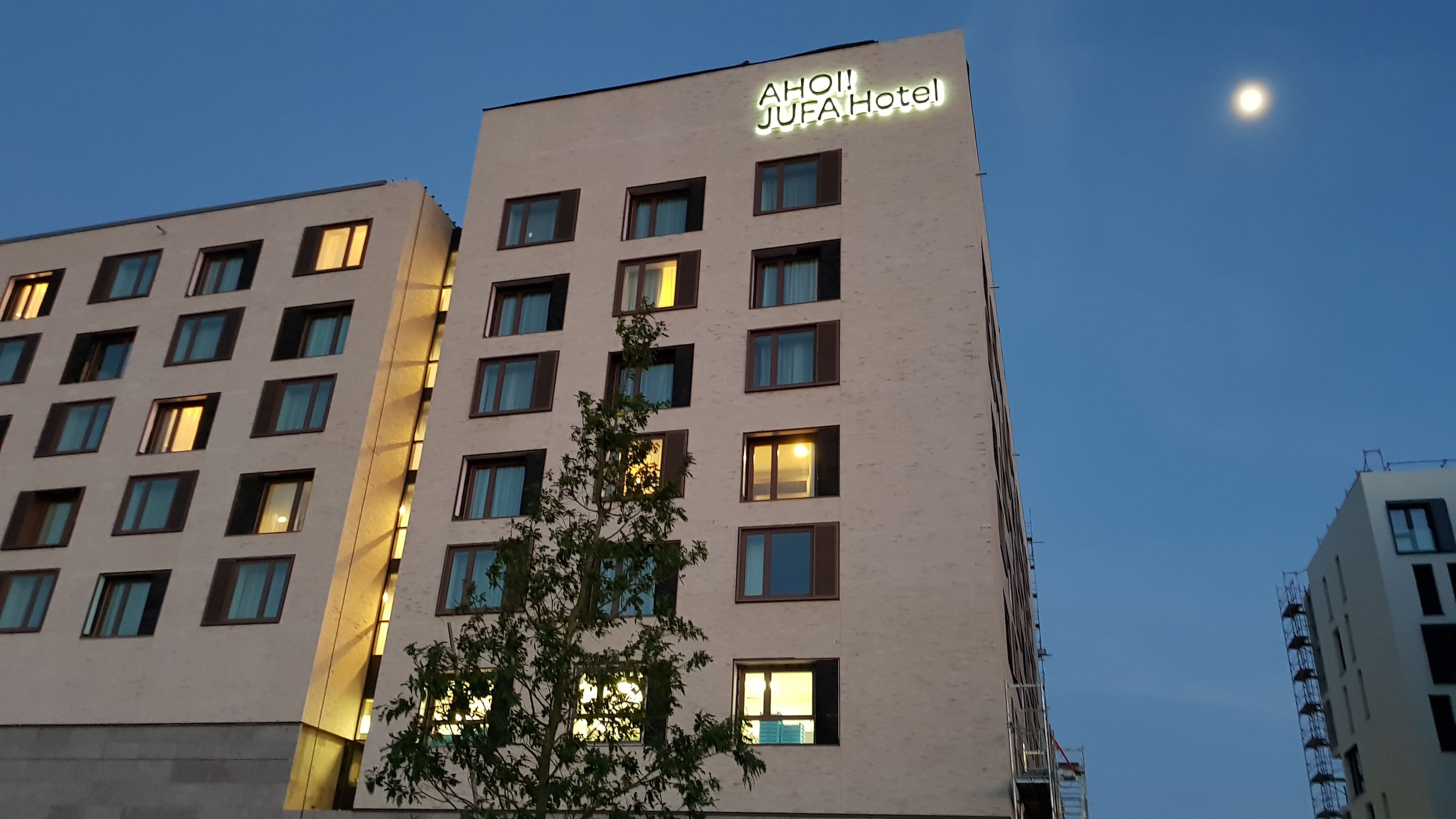 Ein mehrstöckiges Hotelgebäude mit einem Schild, auf dem 'AHOI JUFAH HOTEL' steht.