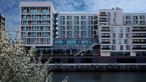 A modern multi-story building with a glass facade, a visible staircase, and a waterfront view.