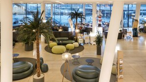 A spacious lobby with seating areas, a palm tree, and a view of the outside.