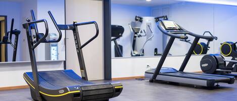 A gym with treadmills, exercise bikes, and weights.