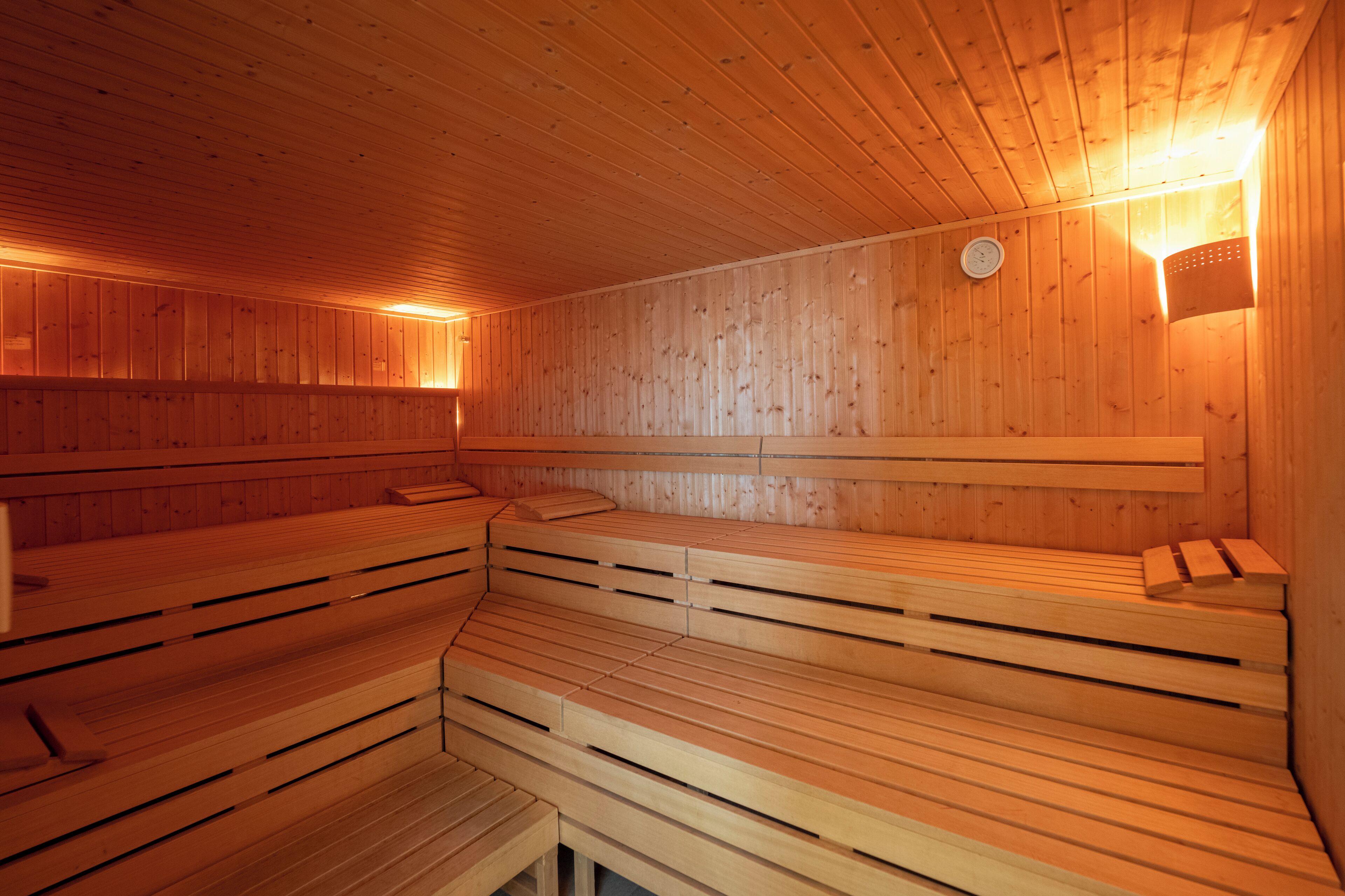 A sauna with wooden benches and a wall-mounted heater.