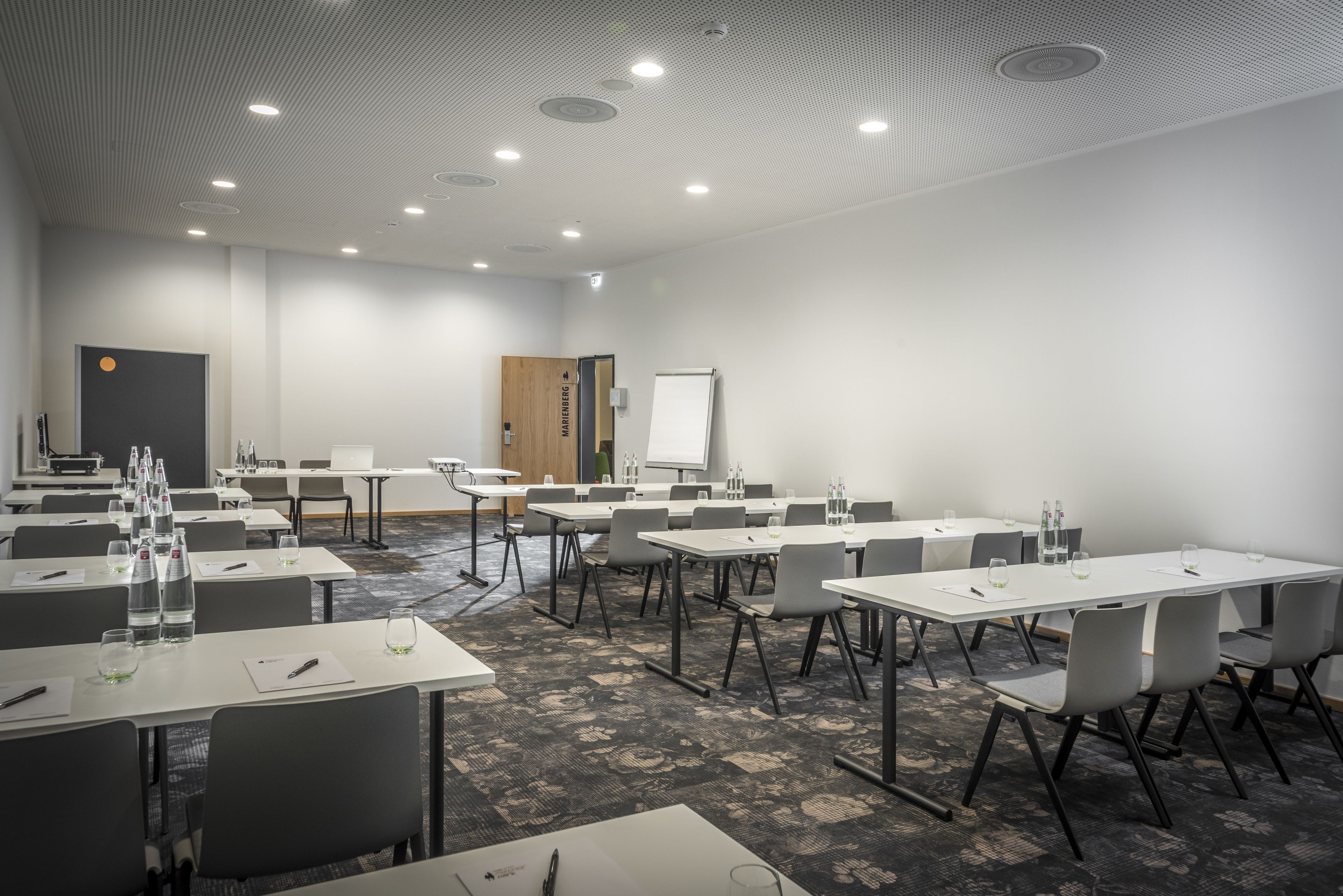 Una sala de conferencias con mesas, sillas, una pizarra y una puerta.