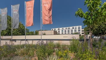 A hotel with multiple flags, a modern building, and a landscaped garden with various plants.