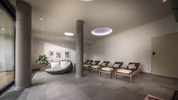 Un espace spa moderne comprenant un comptoir d’accueil, des fauteuils et une grande plante.