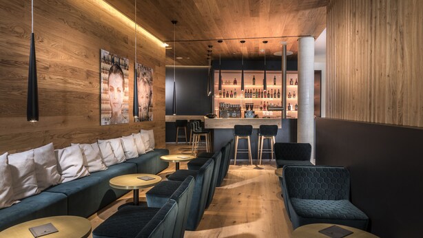 A modern bar area with wooden walls, seating, and a bar counter.