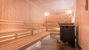A sauna with wooden benches and a small wooden bucket.