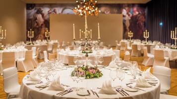 A banquet hall with round tables, white tablecloths, and candle centerpieces.
