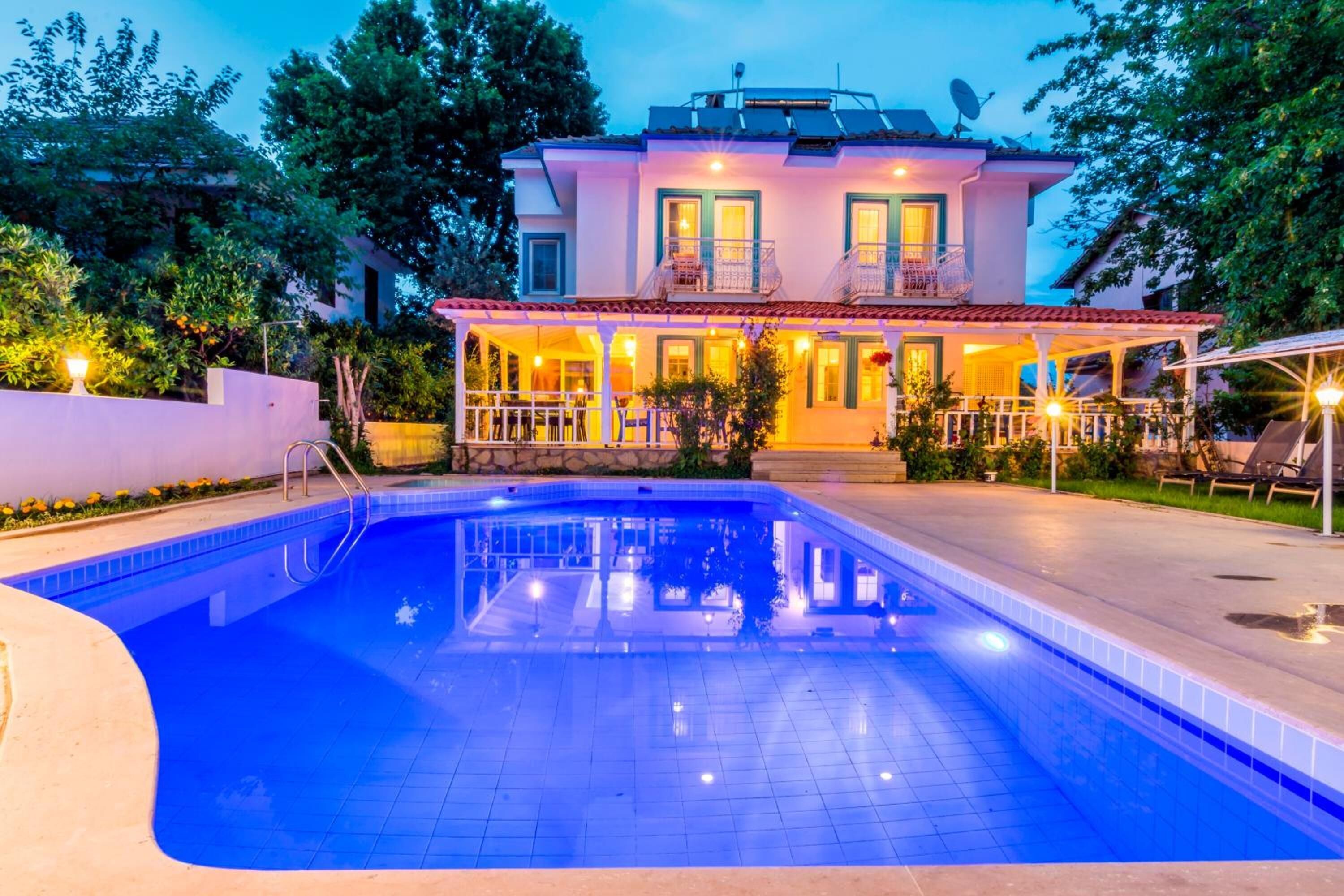A two-story house with a swimming pool, a covered patio, and a garden.