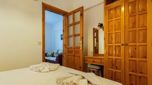 A hotel room with a bed, a wooden wardrobe, a small desk, and a mirror. - Calypso Cozy Suites (Ortaca)