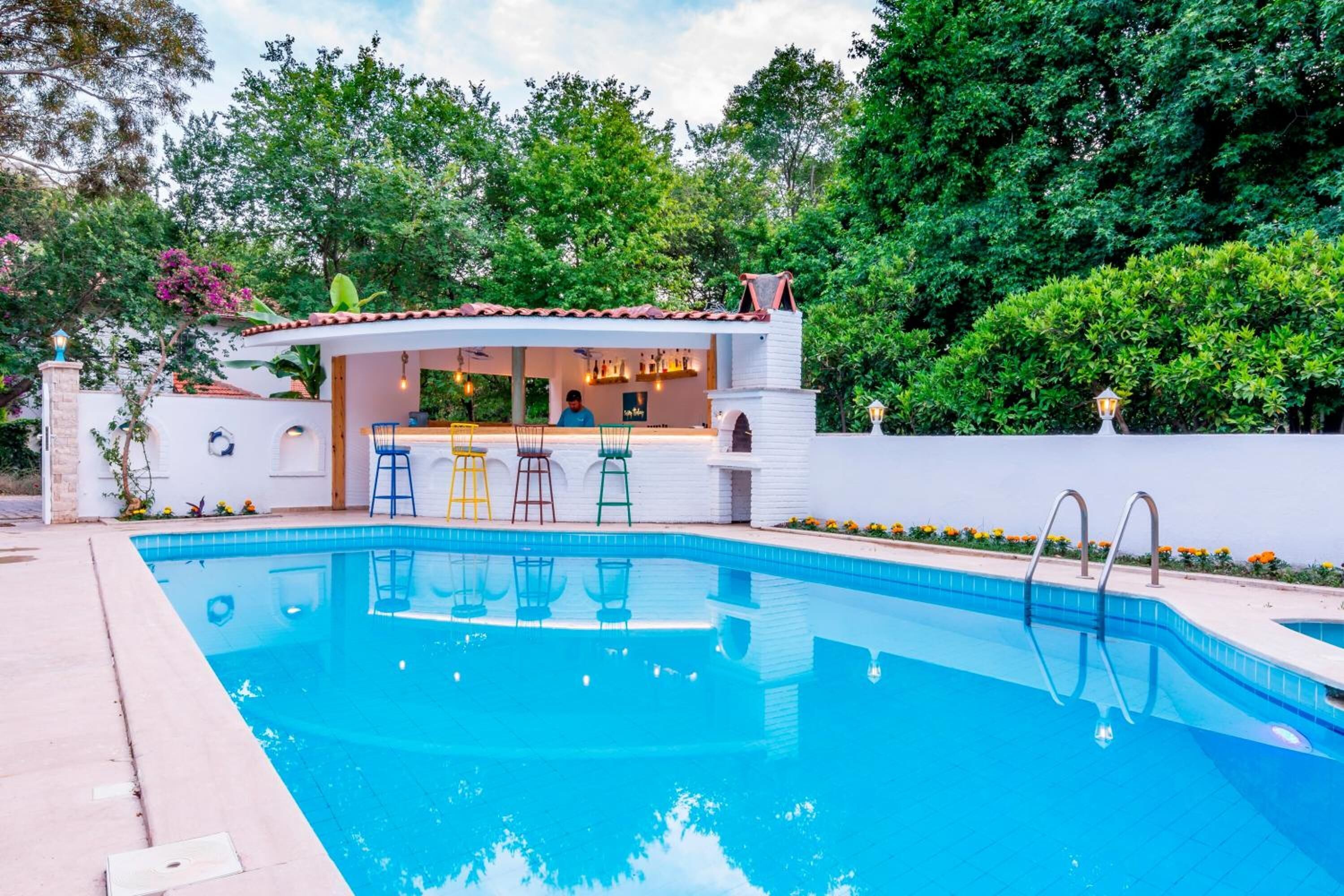 A swimming pool with a bar area, surrounded by greenery.
