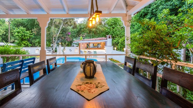 A covered outdoor dining area with a pool in the background. - Calypso Cozy Suites (Ortaca)