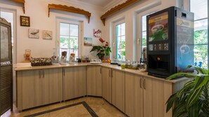 A kitchen with wooden cabinets, a coffee machine, and a window with a view of greenery. - Calypso Cozy Suites (Ortaca)