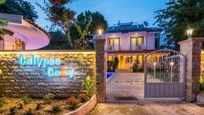 A hotel entrance with a stone wall and a neon sign reading "Calypso Cozy". - Calypso Cozy Suites (Ortaca)