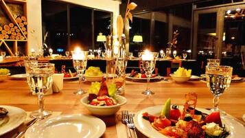 Mesa de comedor dispuesta con platos, vasos y cubiertos, con un tazón de ensalada y una botella de agua.