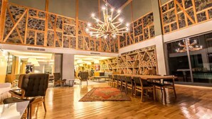 A spacious lobby with a high ceiling, wooden beams, a central chandelier, and a seating area with tables and chairs. - Abant Lotus Otel (Bolu)