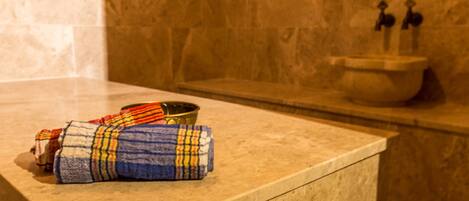 A bathroom with a marble countertop, a towel, and a basin with faucets.