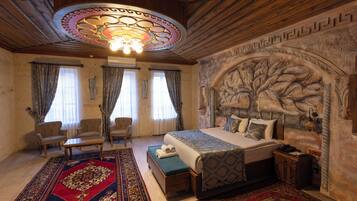 Een slaapkamer met een groot bed, twee fauteuils, een houten plafond en een decoratieve wand.