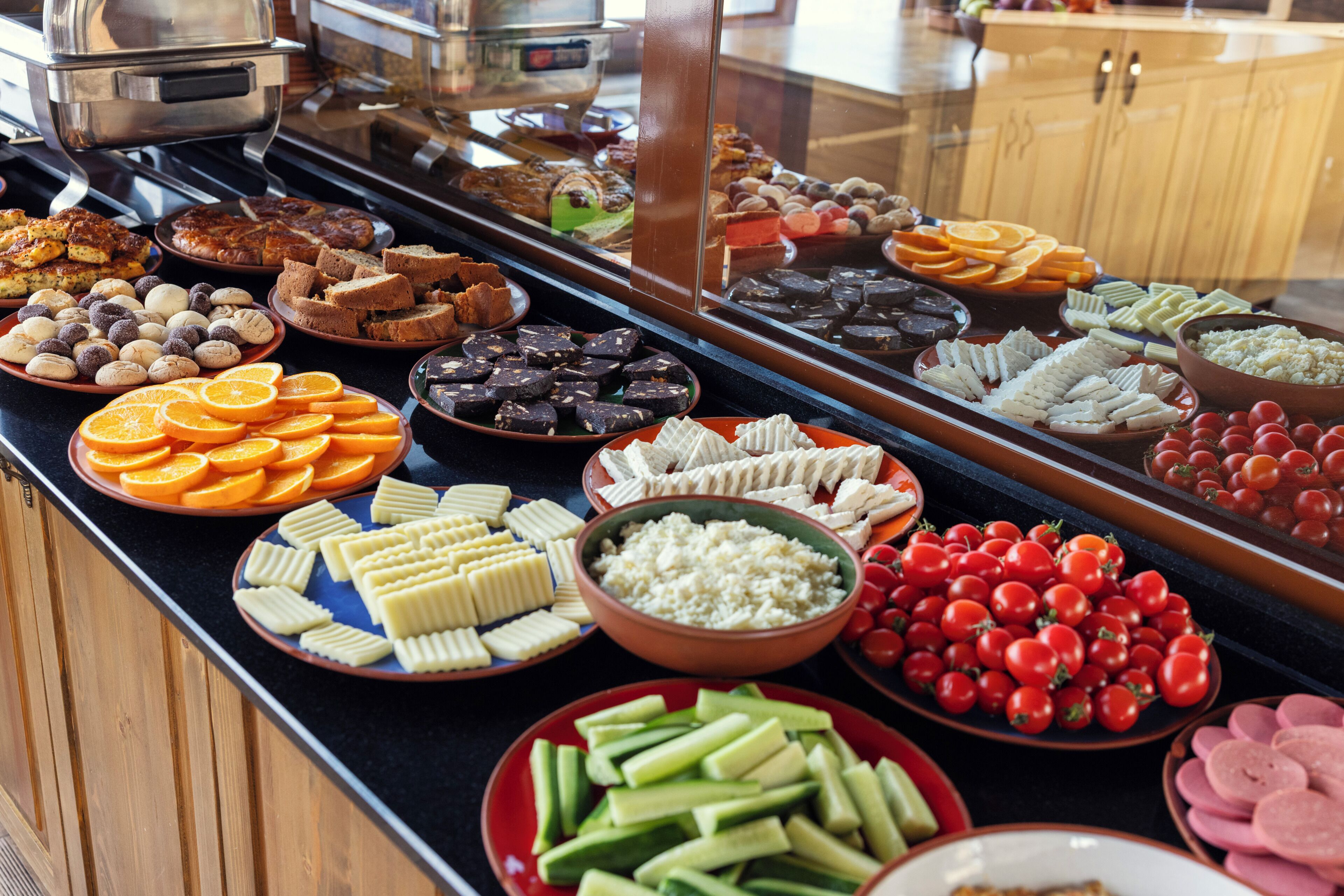 A buffet with various food items including fruits, cheeses, and meats.