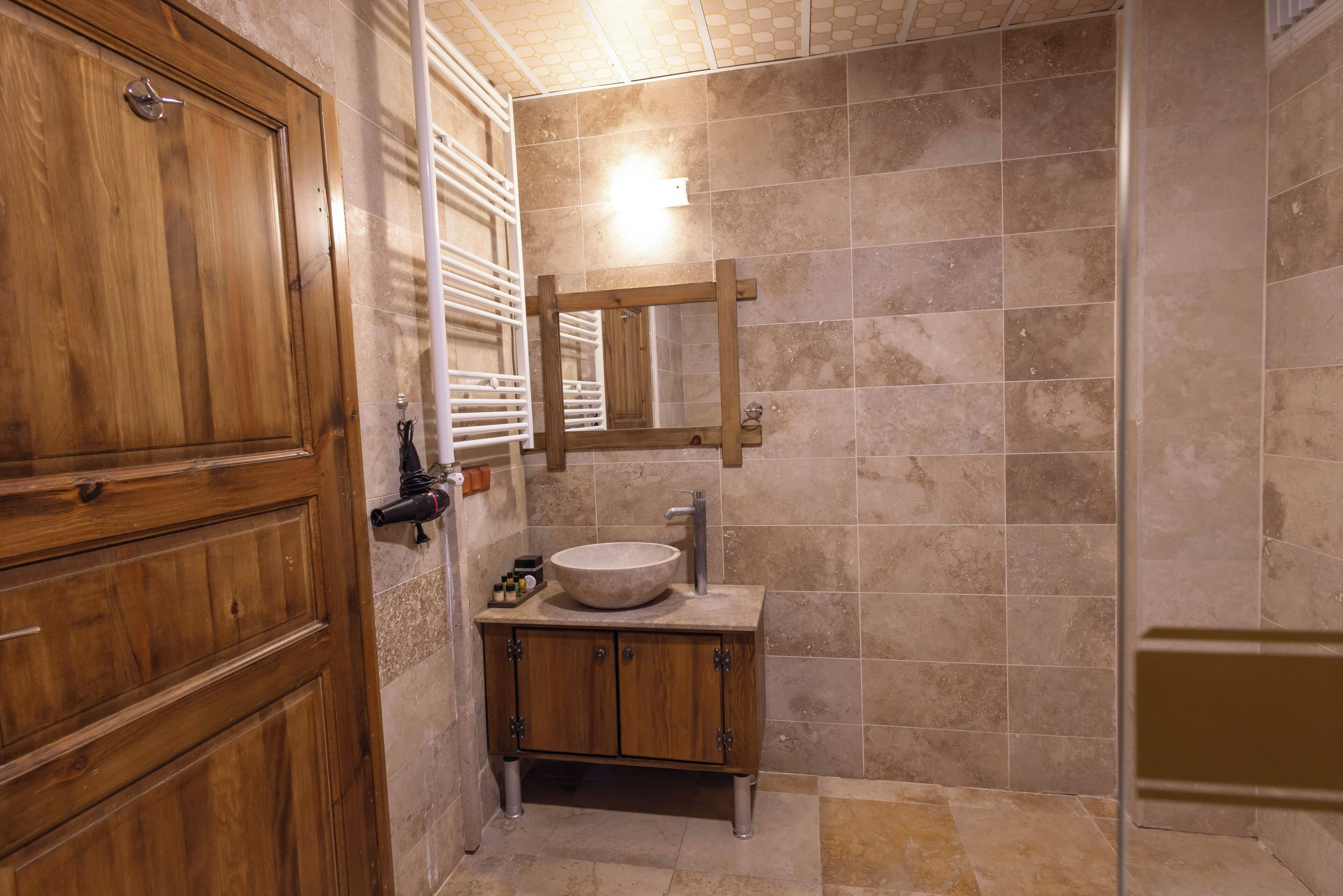Un baño con puerta de madera, un lavabo con espejo y paredes con azulejos.