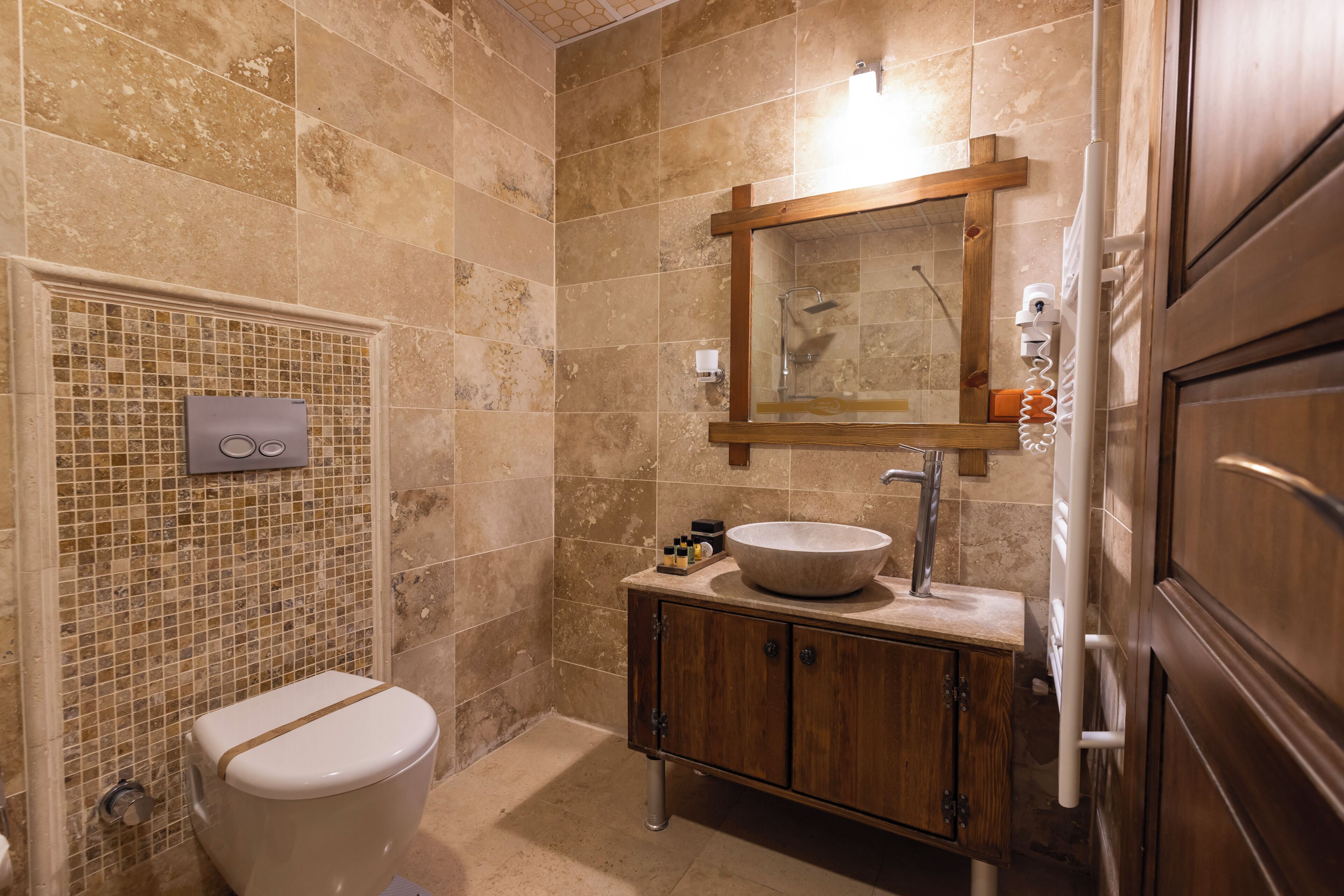 A bathroom with a toilet, sink, mirror, and shower.