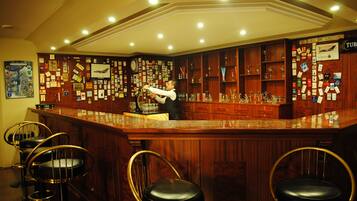 Un espace bar avec des lambris en bois, un barman et des tabourets de bar.