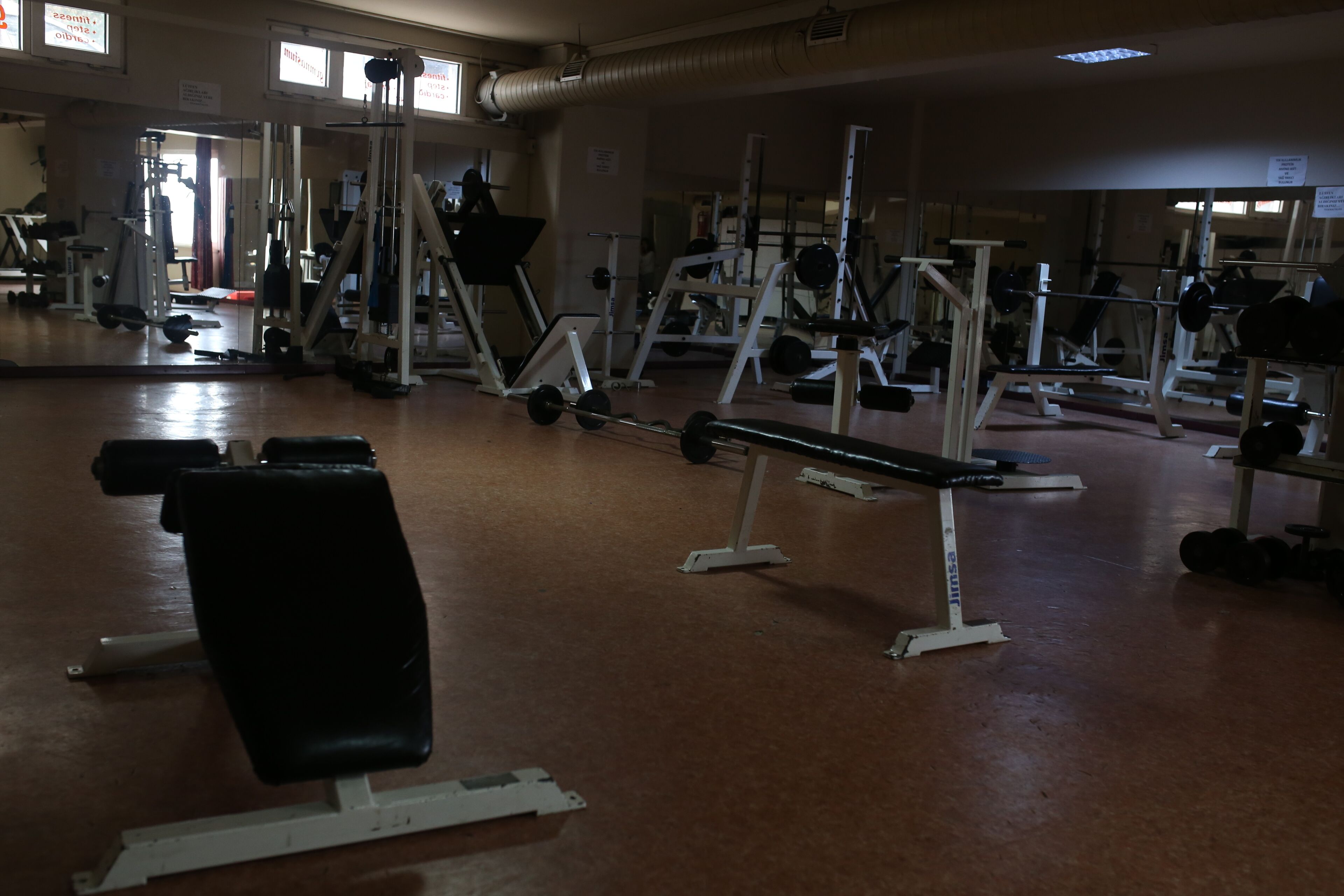 Une salle de sport équipée de divers appareils d’exercice, notamment des bancs, des machines de musculation et des poids libres.