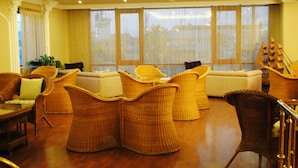 A spacious living room with wicker furniture, large windows with curtains, and a ceiling with recessed lighting. - Hotel Eken Prestige (Bandirma)